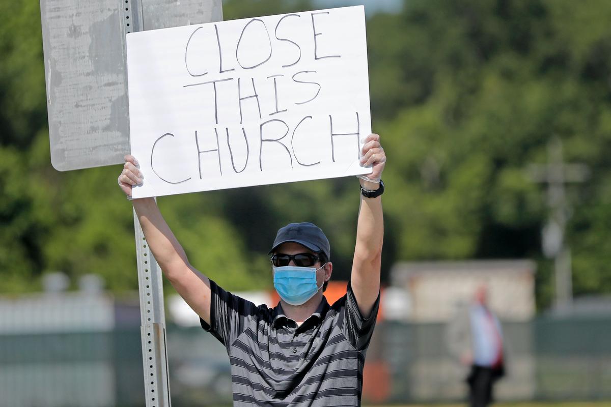  Protestor Trey Bennett holds a sign towards members of the Life Tabernacle Church waiting outside the East Baton Rouge Parish jail for Pastor Tony Spell to post bond in Baton Rouge, La., on April 21, 2020. (Gerald Herbert/AP photo)