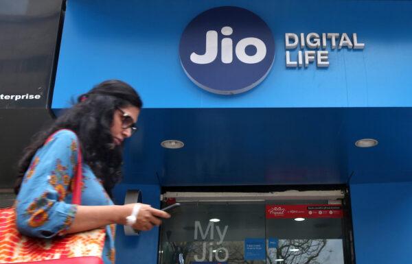 A woman checks her mobile phone as she walks past a mobile store of Reliance Industries' Jio telecoms unit, in Mumbai, India, July 11, 2017. (Reuters/Shailesh Andrade)