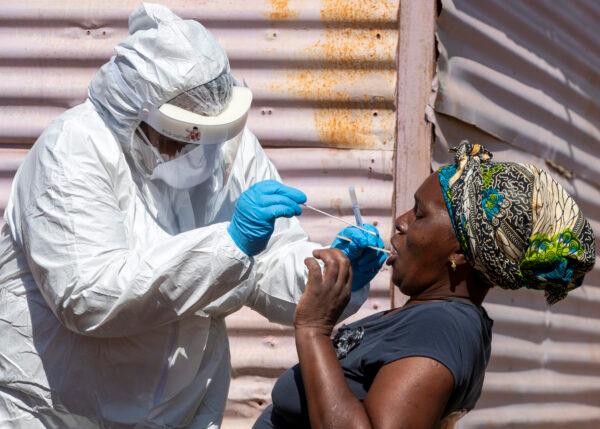 A woman opens her mouth for a health worker to collect a sample for CCP virus testing during the screening and testing campaign at Lenasia South, south Johannesburg, South Africa, on April 21, 2020. (Themba Hadebe/AP Photo)