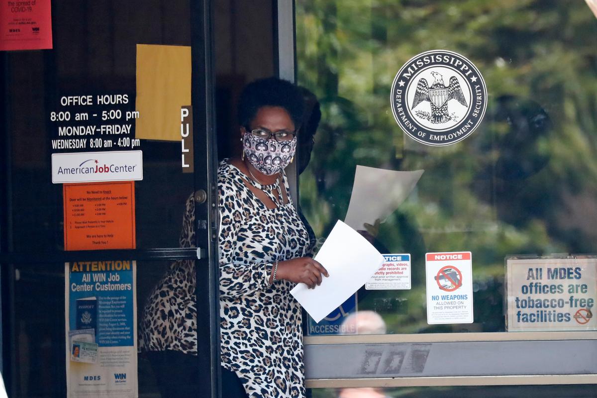 A masked worker at this state WIN job center holds an unemployment benefit application form as she waits for a client in Pearl, Miss., on April 21, 2020. (Rogelio V. Solis/AP Photo)