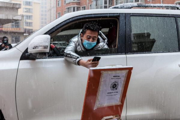 A driver scanning a QR code to register information before entering a community during snowfall in the border city of Suifenhe in China's northeastern Heilongjiang Province on April 22, 2020. (STR/AFP via Getty Images)
