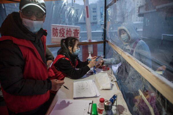 A staff member (C) checking the body temperature of a woman before she enters a community in the border city of Suifenhe in China's northeastern Heilongjiang province on April 22, 2020. (STR/AFP via Getty Images)