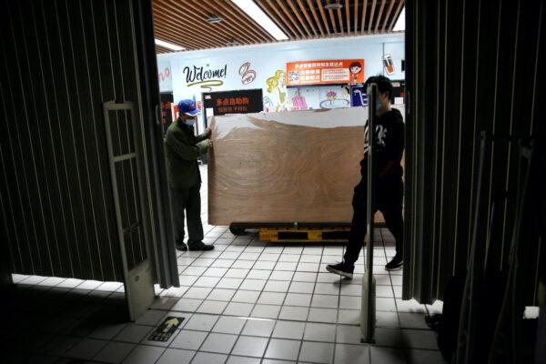 Workers wearing face masks move wood planks from a clothing store after it went out of business following the COVID-19 outbreak, in Beijing, China, on April 17, 2020. (Tingshu Wang/Reuters)