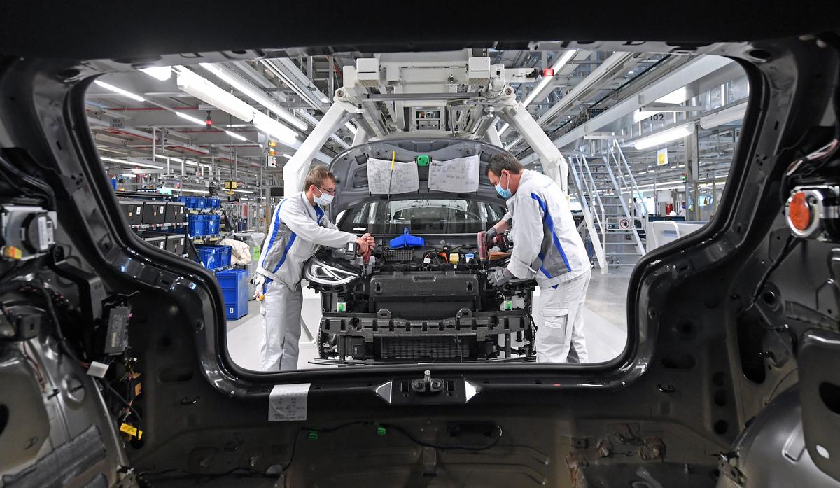 Max Bruehmann, left, and Heiko Gruner employees of German car producer Volkswagen Sachsen, work with face masks in the assembly of the ID.3 in the vehicle plant in Zwickau, Germany, on April 23, 2020. (Hendrik Schmidt/dpa via AP)