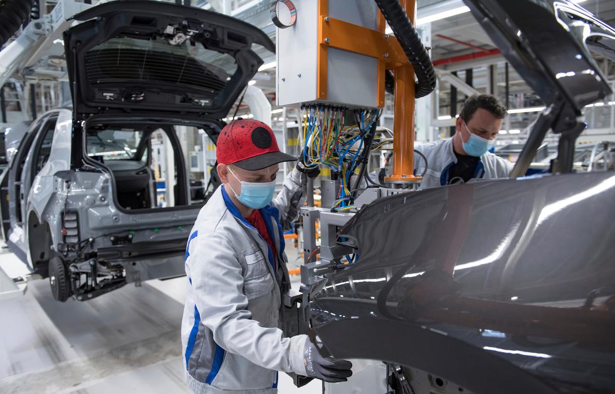 Sebastian Lohse, left, and Heiko Gruner employees of German car producer Volkswagen Sachsen, work with face masks in the assembly of the ID.3 in the vehicle plant in Zwickau, Germany, on April 23, 2020. (Hendrik Schmidt/dpa via AP)