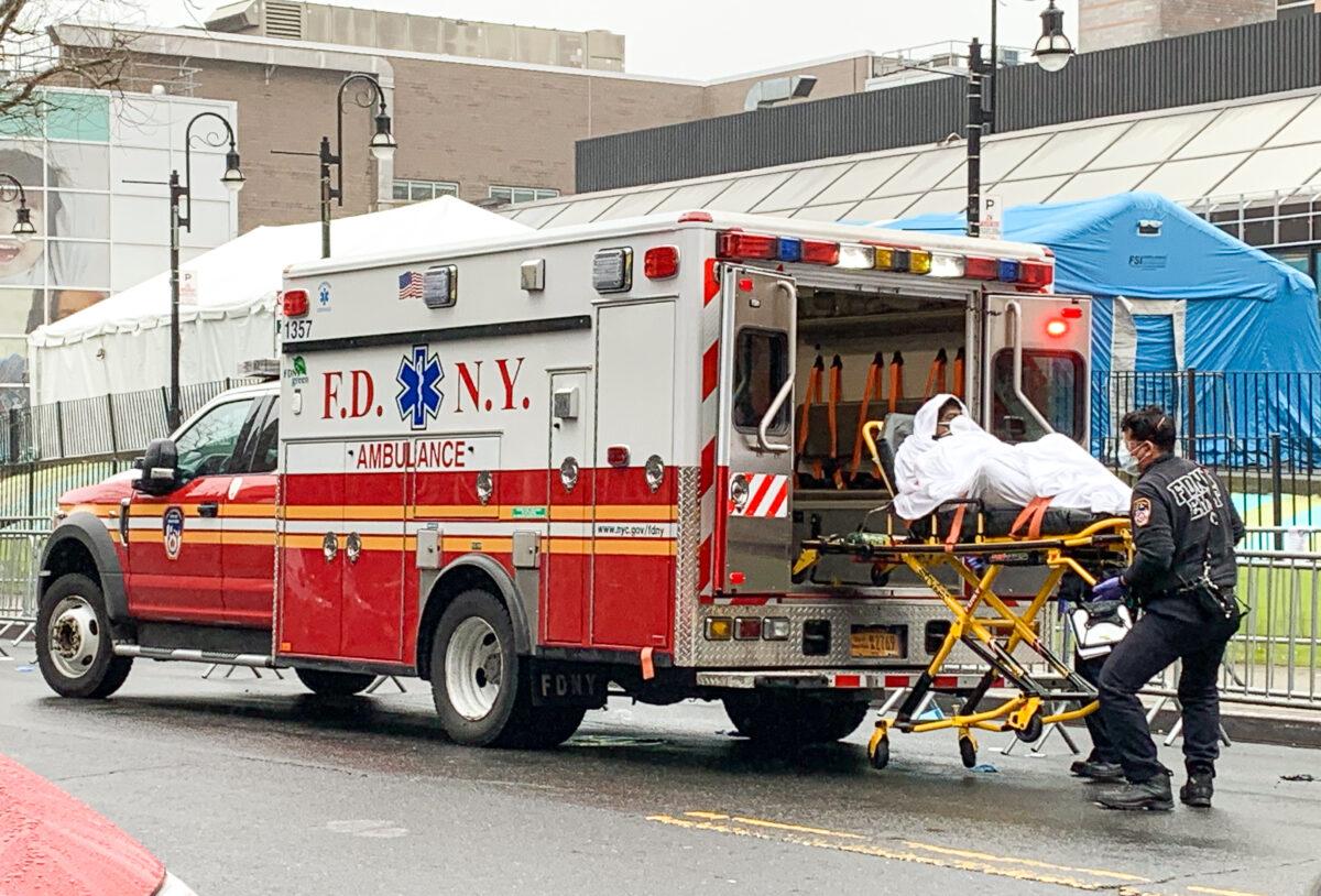 Health workers carry a patient out of an ambulance in front of the Elmhurst Hospital Center in Elmhurst, New York, on March 29, 2020. (Chung I Ho/The Epoch Times)