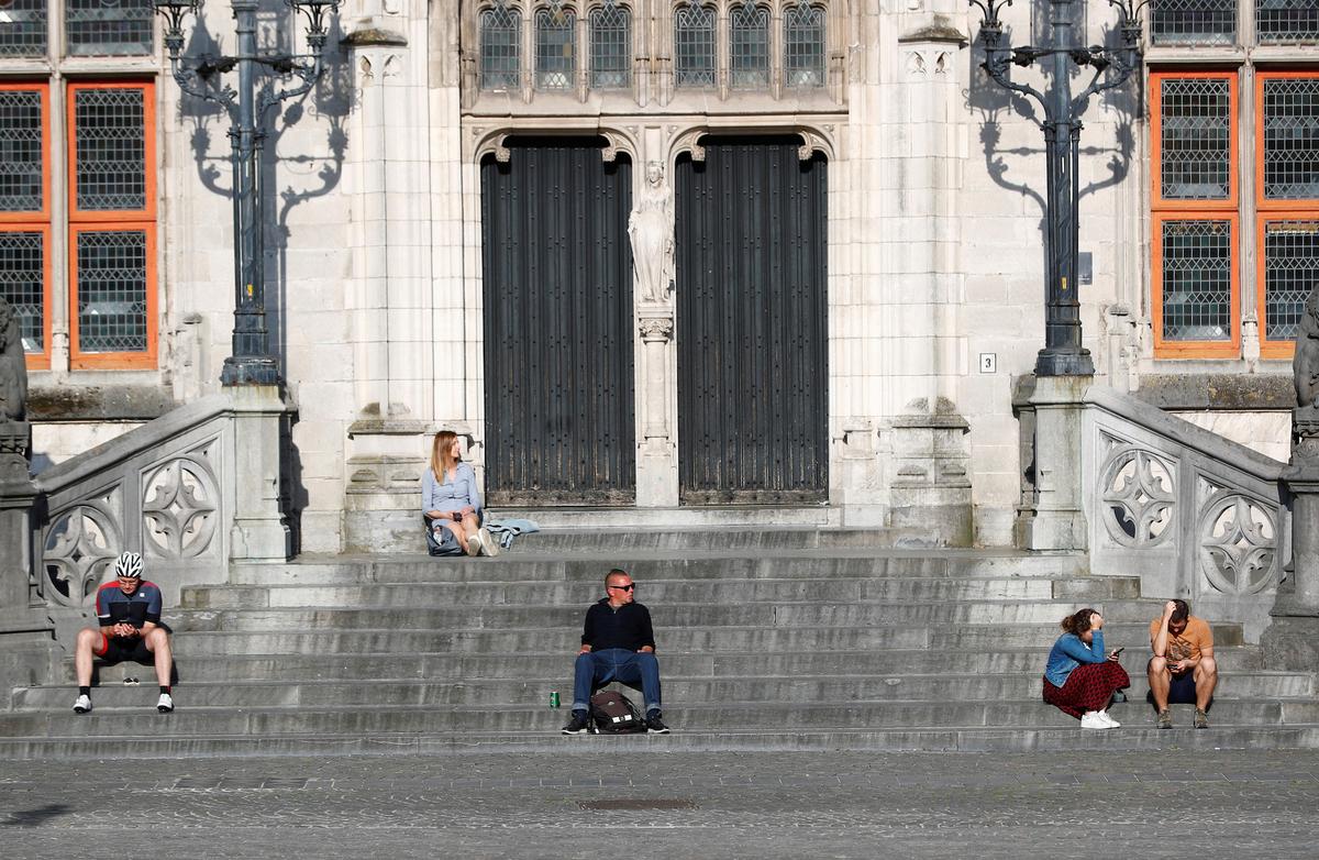 People observe social distancing as they sit on a square in Bruges, Belgium, April 21, 2020. (REUTERS/Francois Lenoir)