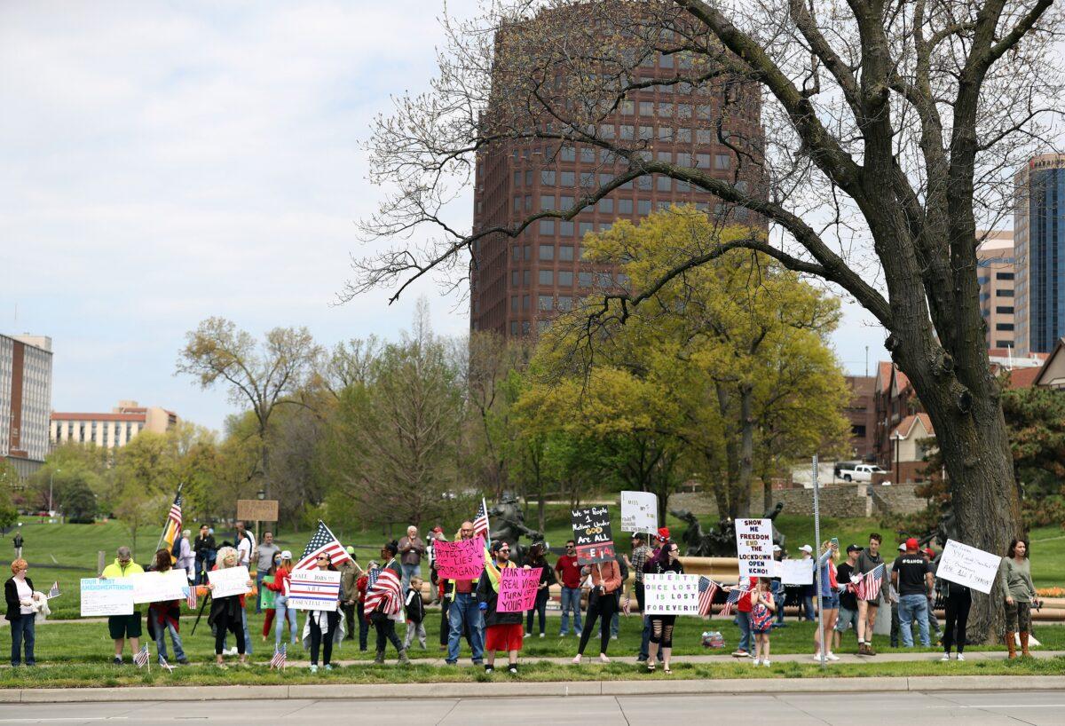 Protesters hold signs encouraging people to demand that businesses be allowed to open up, and people allowed to go back to work, at the Country Club Plaza in Kansas City, Mo., on April 20, 2020. (Jamie Squire/Getty Images)