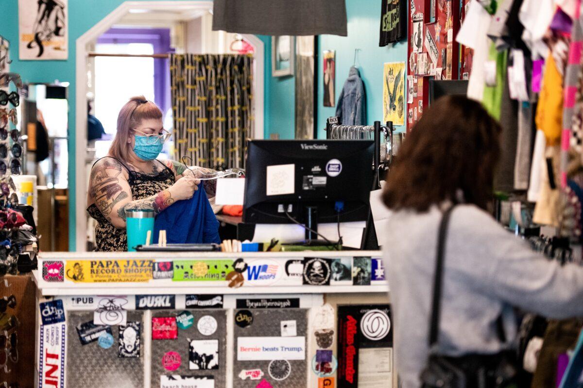 Megan Yelton works at Sid and Nancy thrift and consignment store as a shopper browses a rack of clothes in Columbia, S.C., on April 23, 2020. (Sean Rayford/Getty Images)