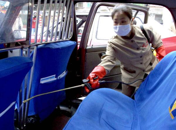 A health worker sprays disinfectant inside a city taxi in Guangzhou, southern China's Guangdong province, on April 16, 2003. (STR/AFP via Getty Images)
