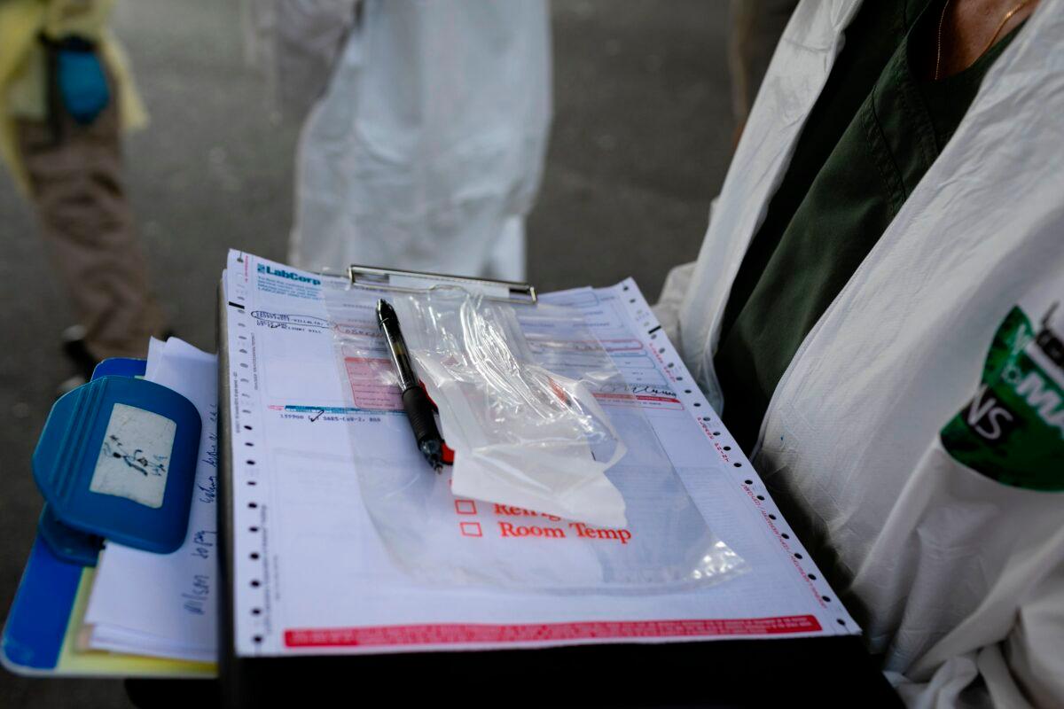 A worker at Miami-Dade County Homeless Trust holds forms for the homeless to sign before being tested for the CCP virus in Miami on April 16, 2020. (Eva Marie Uzcategui/AFP via Getty Images)
