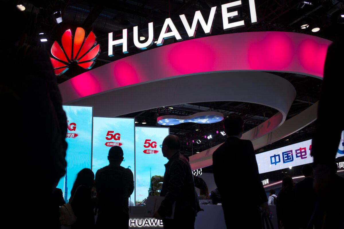 Attendees walk past a display for 5G services from Chinese technology firm Huawei at the PT Expo in Beijing. Chinese tech giant Huawei says its 2019 sales rose 19.1 percent over a year earlier despite U.S. sanctions that hampered its smartphone and network equipment businesses. (Mark Schiefelbein/AP Photo)