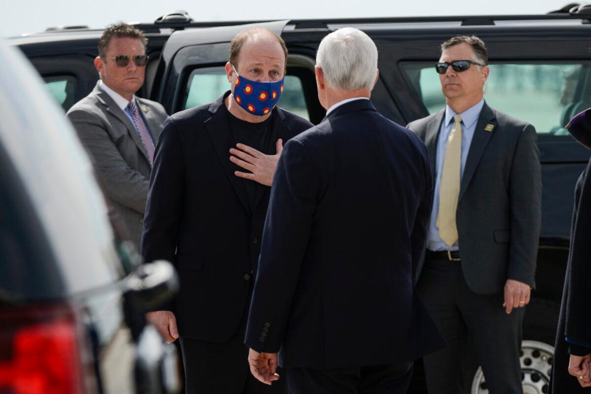 Colorado Gov. Jared Polis (L) speaks with Vice President Mike Pence as he arrives at Peterson Air Force Base before giving a graduation address at the Air Force Academy in Colorado Springs on April 18, 2020. (Michael Ciaglo/Getty Images)