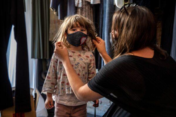 A boutique shopkeeper Xana Yva Zepplin puts on a protective mask to her daughter as she prepares to open her "Rau Berlin" store for the first time since March during the COVID-19 pandemic in Berlin, Germany, on April 22, 2020. (Maja Hitij/Getty Images)