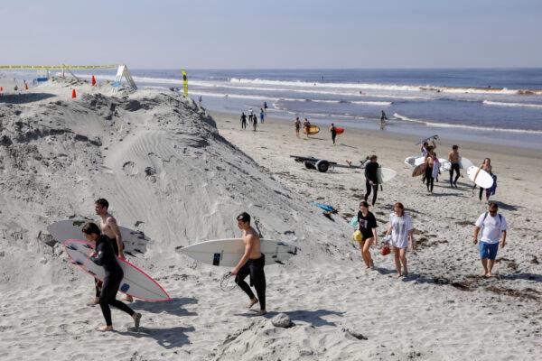 Surfers leave a beach after officials opened it during the outbreak of the CCP virus (COVID-19) in Encinitas, Calif., on April 27, 2020. (Mike Blake/Reuters)