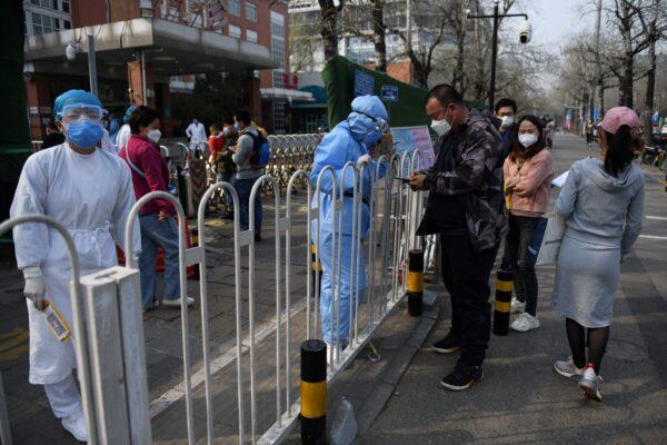 Hospital staff (L) registers patients on the sidewalk outside a children's hospital in Beijing on March 31, 2020. (GREG BAKER/AFP via Getty Images)