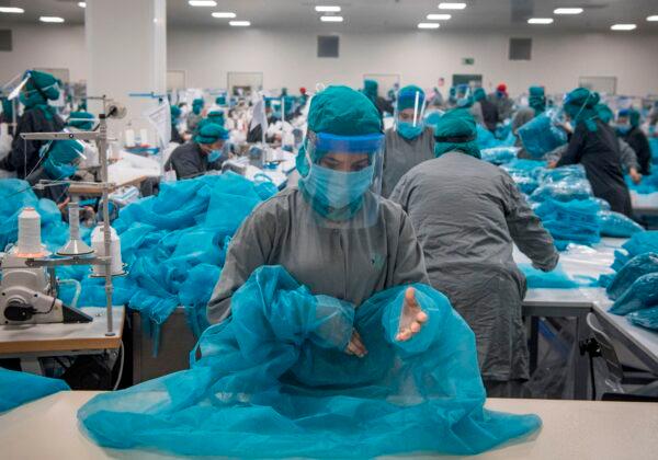 Workers in a factory, wearing surgical masks and face shields due to the CCP virus pandemic, produce gowns and other protective gear to be used by paramedics and first responders, in the city of Berrechid, south of Casablanca, Morocco, on April 16, 2020. (Fadel Senna/AFP via Getty Images)