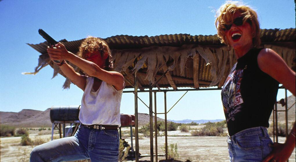 Louise (Susan Sarandon, L) flattens a trucker's tires as Thelma (Geena Davis) looks on delightedly, in “Thelma & Louise.” (MGM)