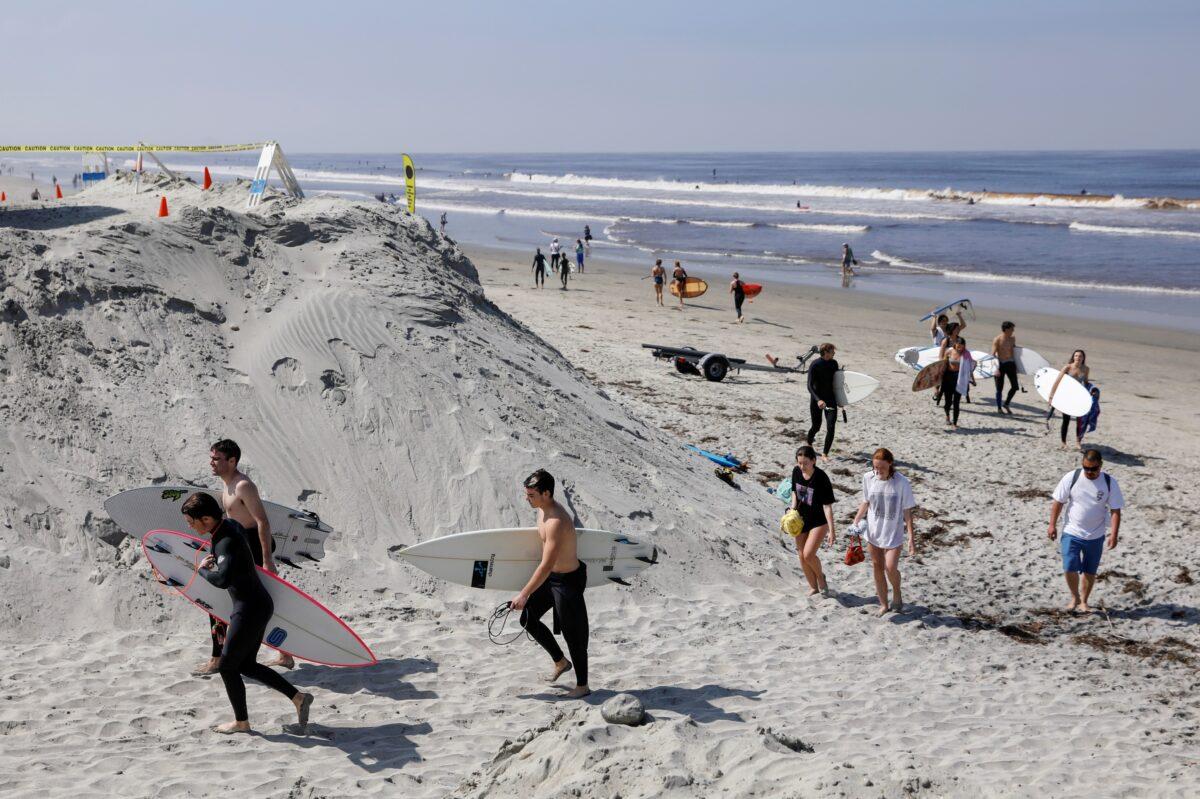 Surfers leave a beach after officials opened it during the outbreak of the CCP virus in Encinitas, California on April 27, 2020. (Mike Blake/Reuters)