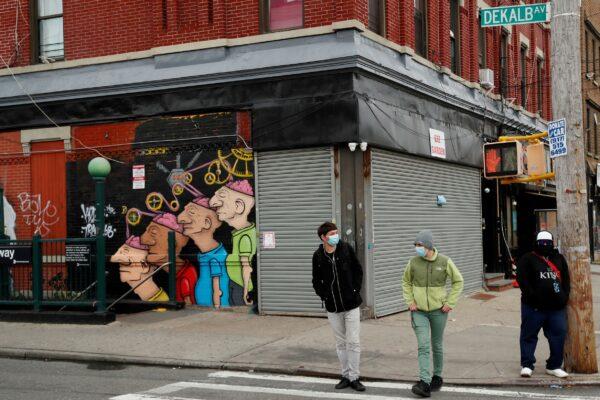Pedestrians wearing masks walk in front of shuttered buildings as the spread of COVID-19 outbreak continues in the Brooklyn borough of New York City, on April 27, 2020. (Lucas Jackson/Reuters)