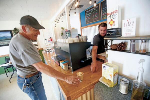 Jonathan Archibald, owner of Mt Taylor coffee (R) sells a cup of coffee to Paul Jackson of grants in Grants, N.M., on April 27, 2020. (Luis Sánchez Saturno/Santa Fe New Mexican via AP)