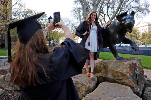 Class of 2020 University of Pittsburgh graduates Shannon Trombley (L) of Philadelphia, and Julie Jones, of West Chester, Pa., take turns posing for photos with a statue of Pitt's mascot, the Pitt Panther, on April 27, 2020. (Gene J. Puskar/AP Photo)