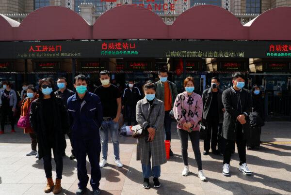 People wearing face masks stand to pay tribute as China holds national mourning for those who died of the coronavirus disease (COVID-19), on the Qingming tomb-sweeping festival, in Beijing on April 4, 2020. (Thomas Peter/Reuters)