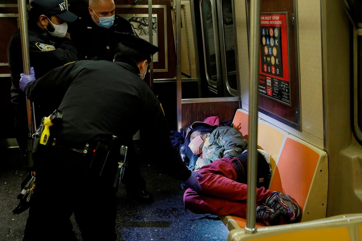 NYPD and MTA officers wake up a sleeping passenger before directing him to exit the 207th Street A-train station, in the Manhattan borough of New York, April 30, 2020. (John Minchillo/ AP Photo)