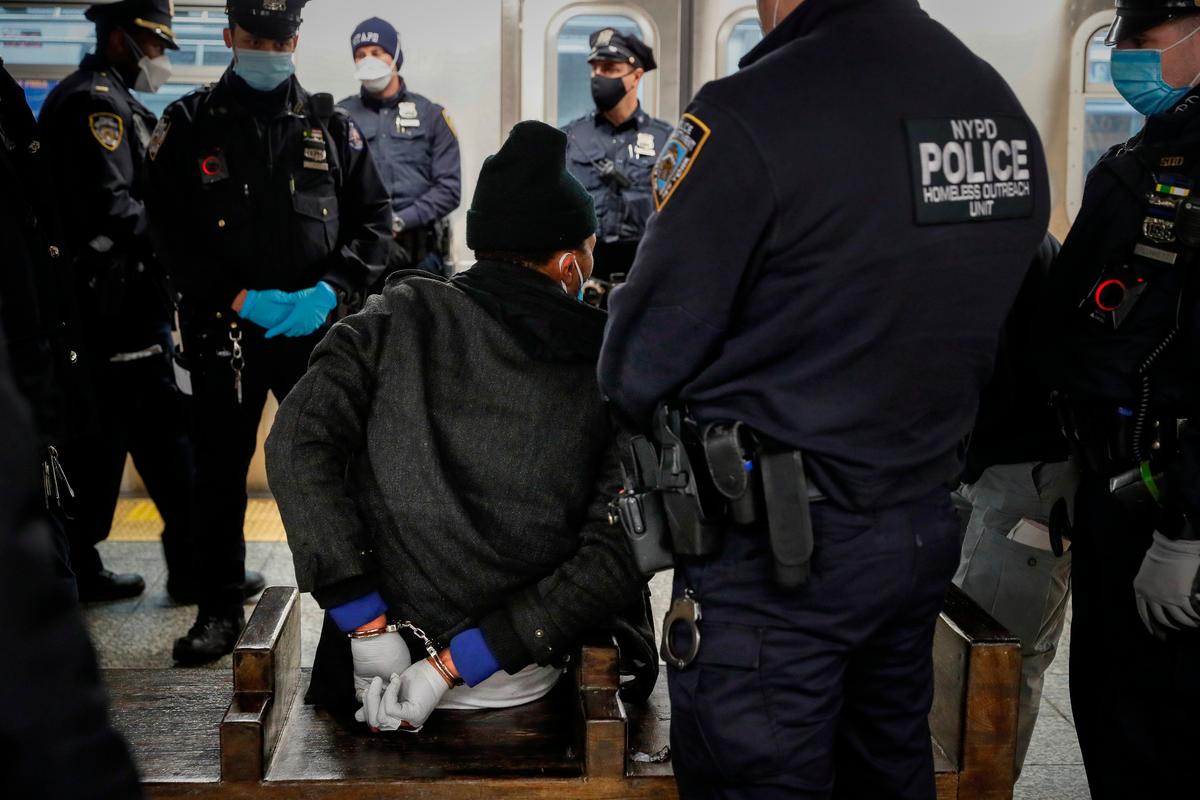 NYPD stand around a passenger who was subdued after he attempted to jump in front of a moving train during an operation to clear cars of sleeping passengers at the 207th Street A-train station, in the Manhattan borough of New York, April 30, 2020. (John Minchillo/AP Photo)