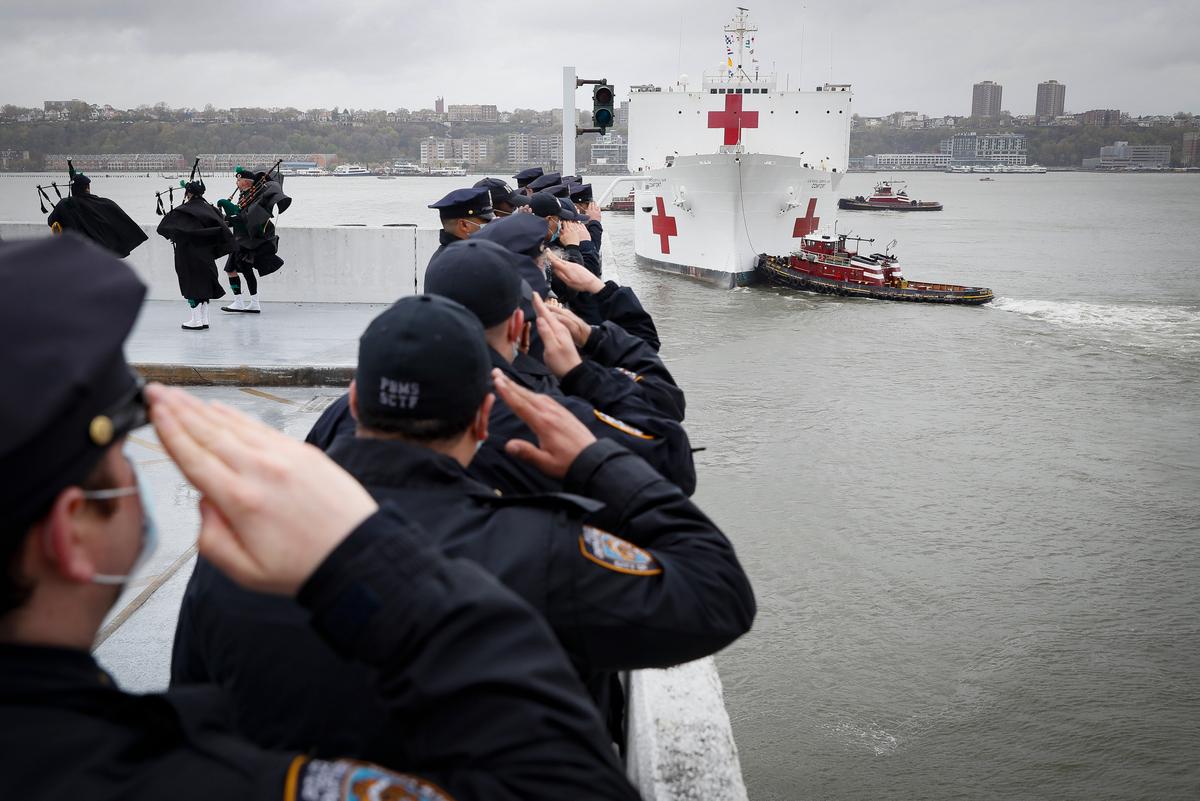 NYPD officers salute the USNS Naval Hospital Ship Comfort as it is pushed out into the Hudson River by tugboats, in the Manhattan borough of New York, April 30, 2020. (John Minchillo/ AP Photo)