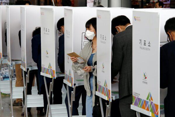 A woman wearing a mask to prevent contracting the coronavirus leaves a voting booth to cast her absentee ballot for the parliamentary election at a polling station in Seoul, South Korea, April 10, 2020. (Heo Ran/Reuters)