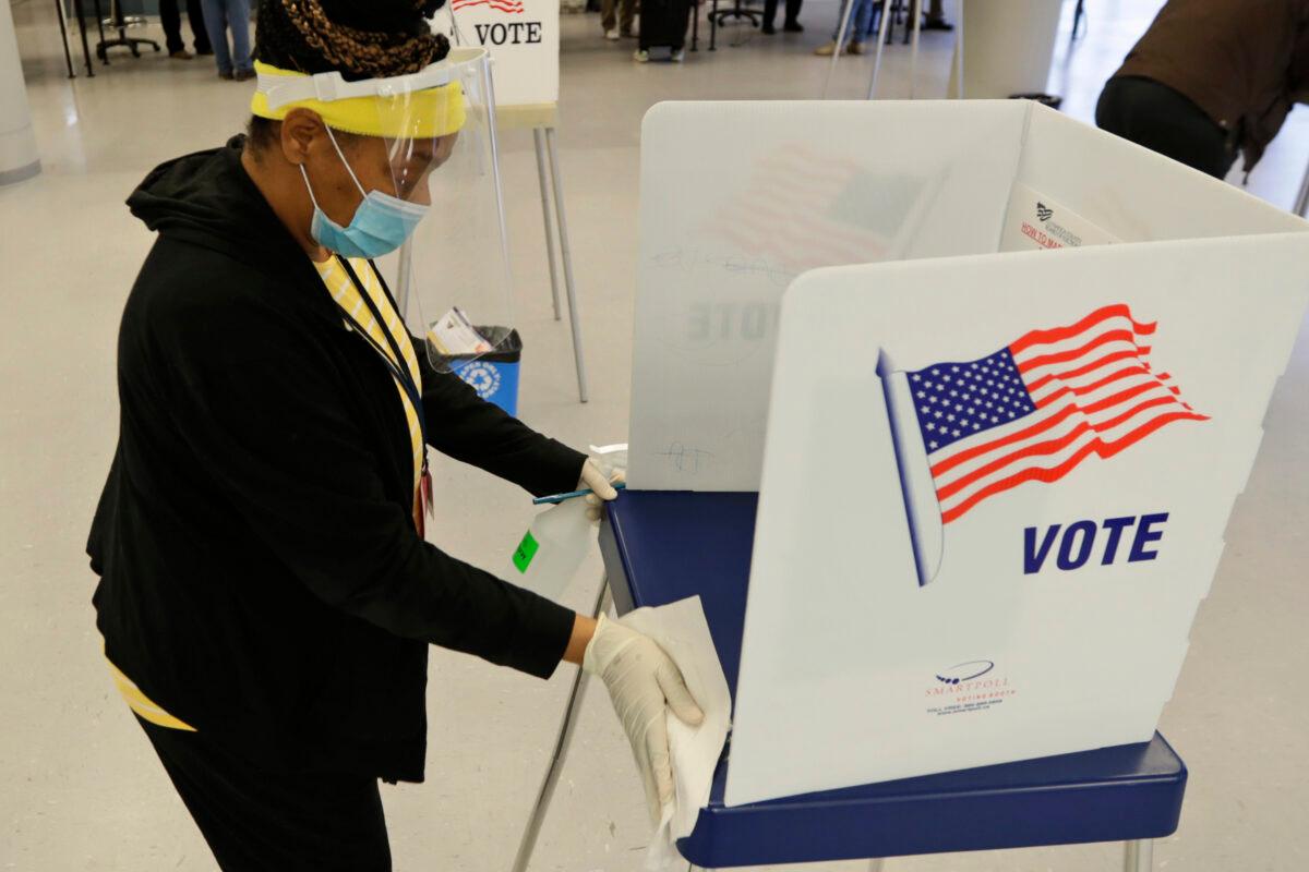 Board of elections worker Valerie Tyree cleans an election booth after a person voted in the state's primary election at the Cuyahoga County Board of Elections, in Cleveland on April 28, 2020. (Tony Dejak/AP Photo)