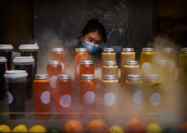  A Chinese juice vendor wears a protective mask as she waits for customers in the heat during the May holiday in Beijing on May 2, 2020. (Kevin Frayer/Getty Images)