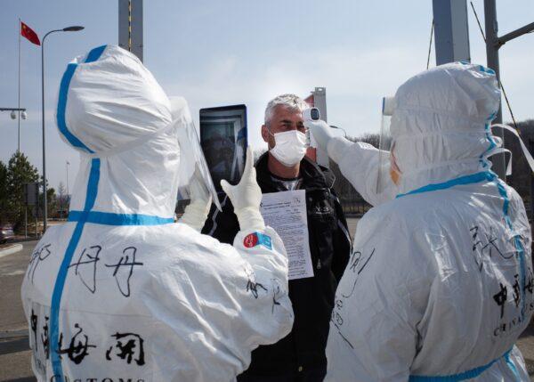Staff wearing hazmat suits are checking the temperature of a driver at a customs checkpoint on the border with Russia at Suifenhe, China, on May 1, 2020. (STR/AFP via Getty Images)