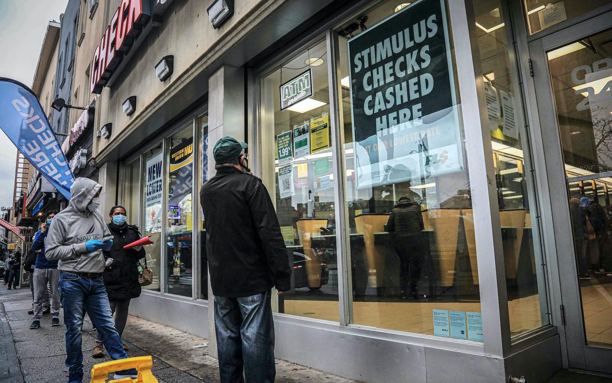 People maintain social distancing and wear protective masks due to COVID-19 concerns while waiting to enter a check cashing service center in the Brooklyn borough of New York on April 24, 2020. (Bebeto Matthews/AP photo)