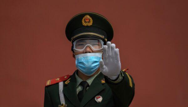 A Chinese paramilitary police officer gestures as he wears a protective mask while standing guard at the entrance to the Forbidden City as it reopened to limited visitors in Beijing, China, on May 1, 2020. (Kevin Frayer/Getty Images)