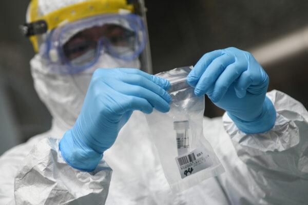 A medical staff member is collecting a sample at a middle school as students receive nucleic acid testing for CCP Virus in Guangzhou, China on April 21, 2020. (STR/AFP via Getty Images)