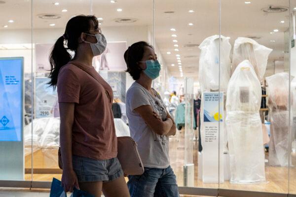 People wearing protective masks walk past a closed retail store in a shopping mall in Singapore on April 6, 2020. (Ore Huiying/Getty Images)