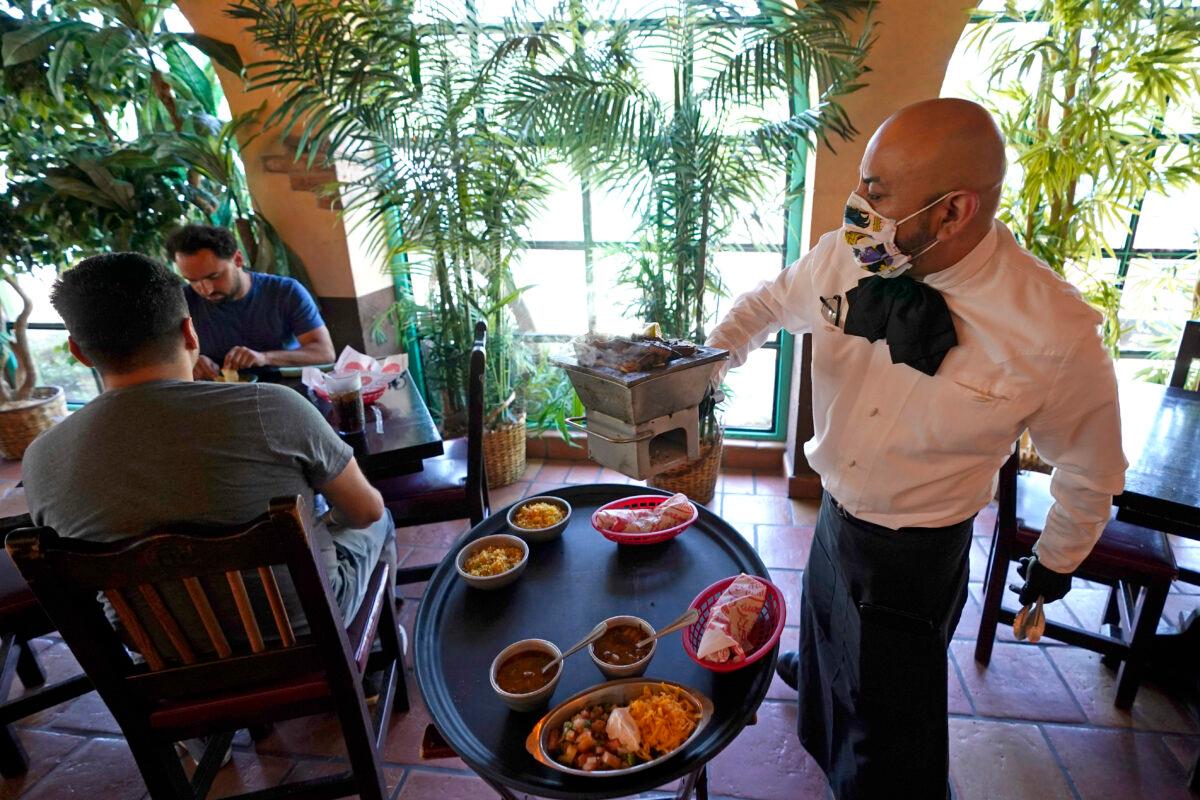 Waiter Marcos Huerta, right, serves a grill of fajitas at El Tiempo Cantina in Houston, on May 1, 2020. (David J. Phillip/AP Photo)