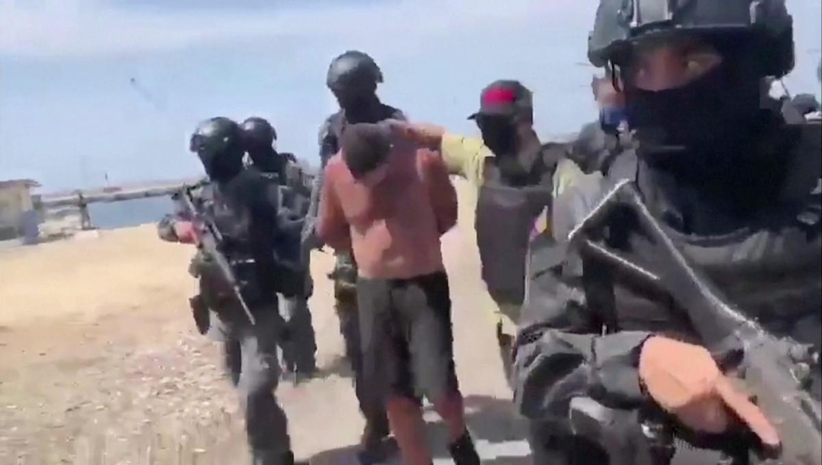 Venezuelan soldiers in balaclavas move a suspect from a helicopter after what Venezuelan authorities described was a "mercenary incursion," at an unknown location in this still frame obtained from Venezuelan government TV video, on May 4, 2020. (Venezuelan Government TV/ Handout via Reuters TV)