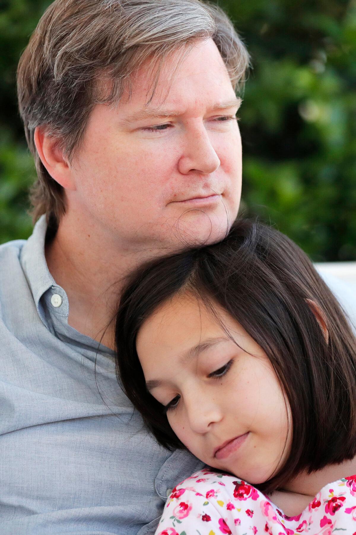 Juliet Daly, 12, sits with her father Sean Daly on the front porch of their family home in Covington, La., on April 30, 2020. (Gerald Herbert/AP Photo)