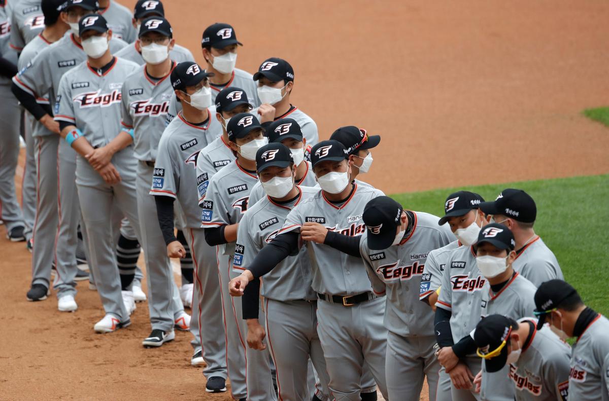 Hanwha Eagles players wearing face masks line up during the start of their regular season baseball game against SK Wyverns in Incheon, South Korea, Tuesday, May 5, 2020. (Lee Jin-man/AP Photo)