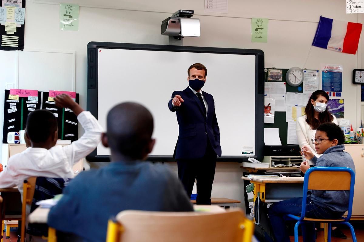 French President Emmanuel Macron wears a protective face mask as he speaks with schoolchildren during a class at the Pierre Ronsard elementary school on May 5, 2020. (Ian Langsdon/Pool/AP)
