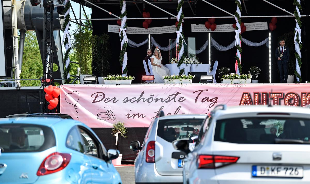 The bridal couple Janine and Philip wait on a stage for mayor Thomas Geisel (right), at their wedding at a Drive-in cinema in Duesseldorf, Germany, May 5, 2020. (Martin Meissner/AP Photo)