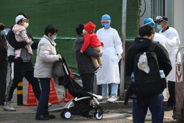 People wait to enter a children's hospital in Beijing, China, on March 31, 2020. (GREG BAKER/AFP via Getty Images)