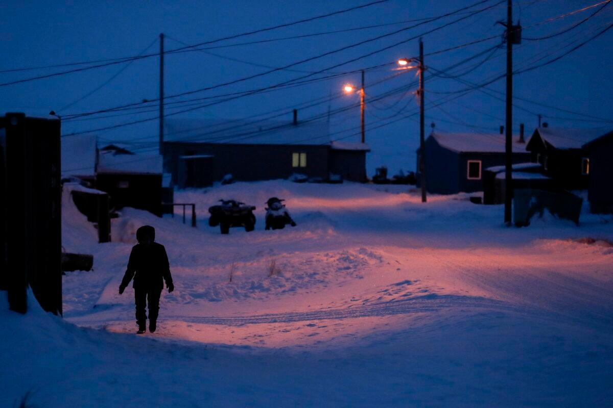 A woman walks before dawn in Toksook Bay, Alaska, on Jan. 20, 2020. (Gregory Bull, File/AP Photo)