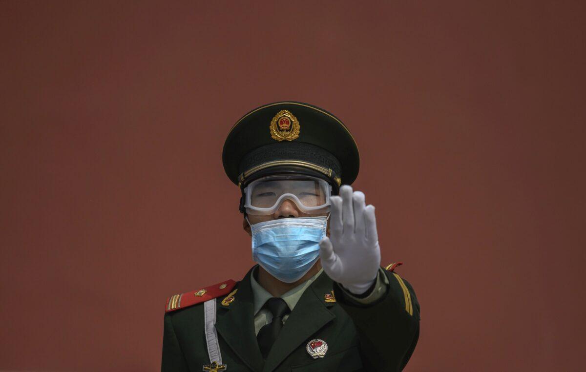 A Chinese paramilitary police officer gestures as he wears a protective mask while standing guard at the entrance to the Forbidden City as it re-opened to limited visitors for the May holiday, on May 1, 2020, in Beijing, China. (Kevin Frayer/Getty Images)