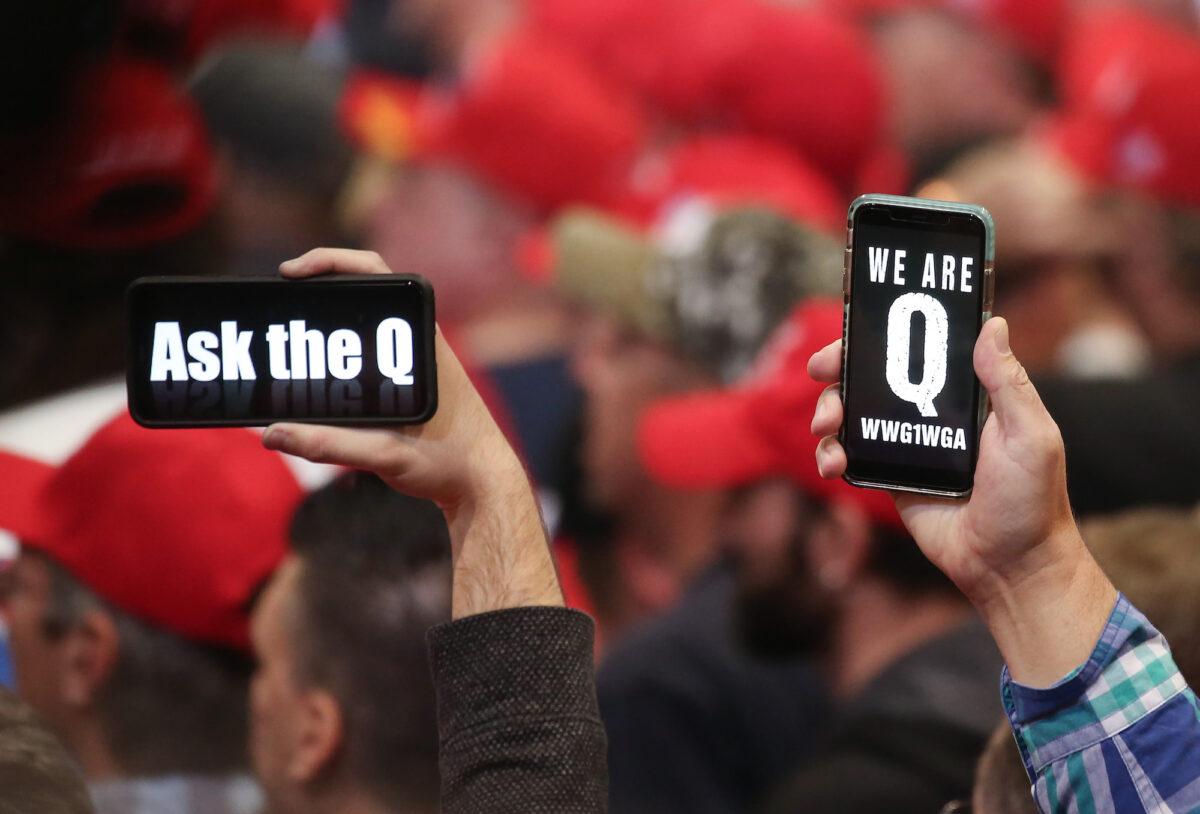 People hold up smartphones with QAnon-related messages on display, at a rally in Las Vegas, on Feb. 21, 2020. (Mario Tama/Getty Images)