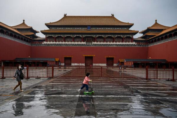 A Chinese girl rides her scooter outside the gates of the Forbidden City, which remains closed to visitors, in Beijing, China, on April 19, 2020. (Kevin Frayer/Getty Images)