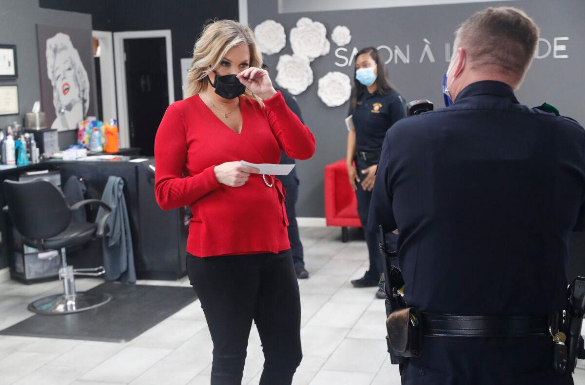 Salon owner Shelley Luther holds a citation and speaks with a Dallas police officer after she was cited for reopening her Salon A la Mode in Dallas, Texas, on April 24, 2020. (LM Otero/AP Photo)